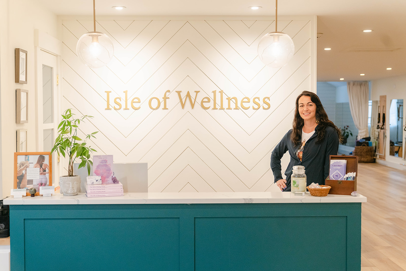 Reception desk with a woman standing behind it in a wellness center, sign reads 'Isle of Wellness'.