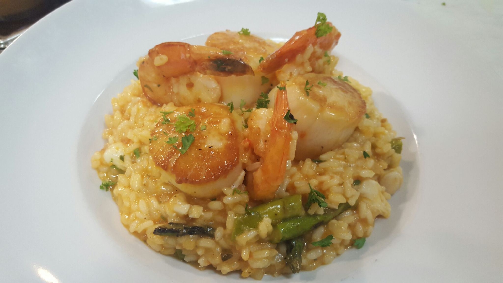 Shrimp and rice dish with green herbs on a white plate.
