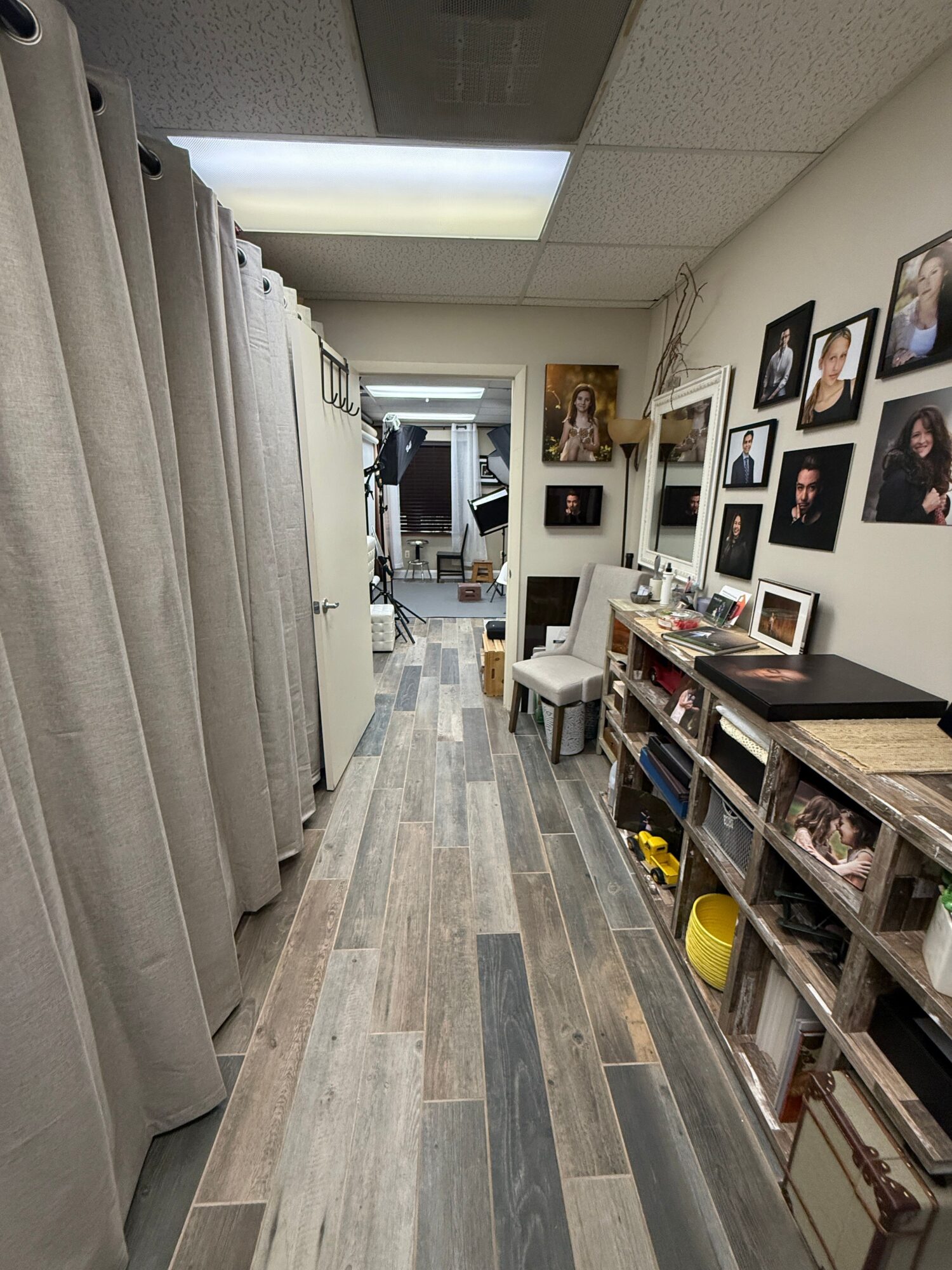 Interior view of a room with a gallery wall of framed photos, a bookshelf, and a wooden floor.