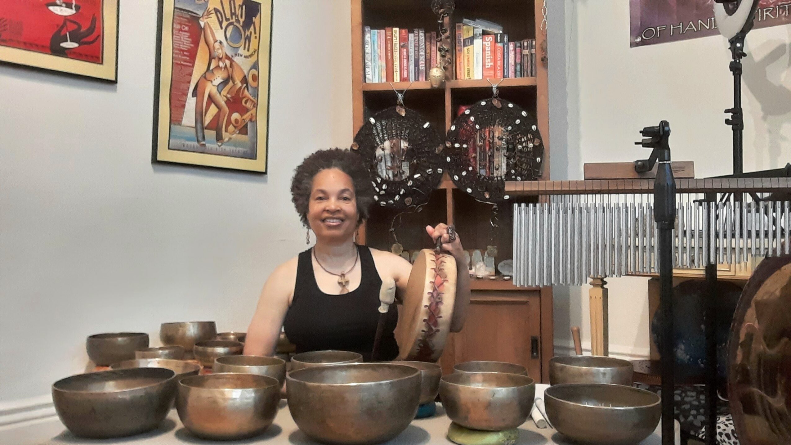 Woman smiling, sitting at a table with multiple bowls, in a room with bookshelves and artwork.