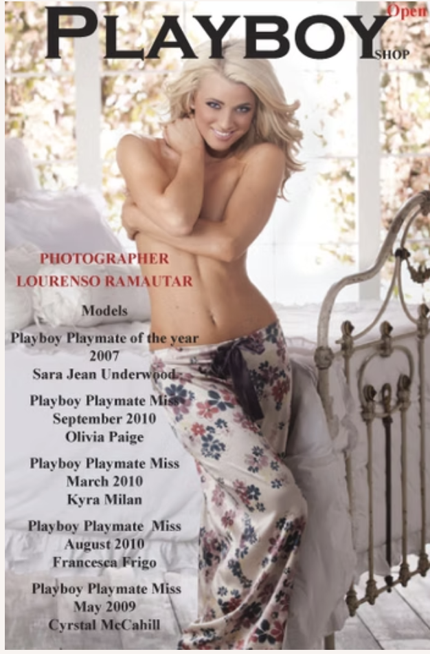 Blonde woman sitting topless on a bed, smiling, with a floral skirt, in a bright room with a window and decorative ironwork.