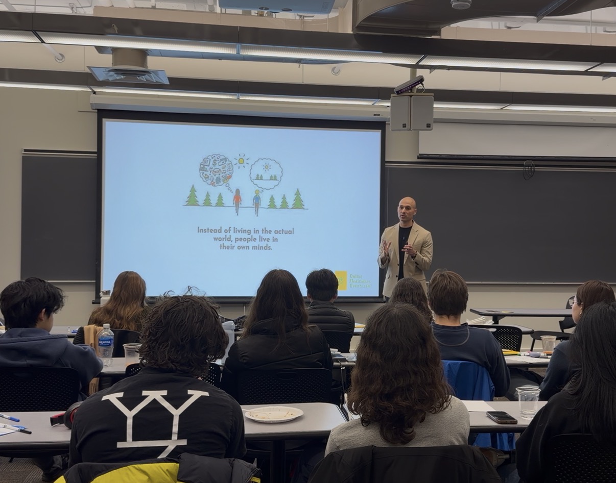 Person standing in front of a classroom giving a presentation, with a slide showing trees and snowflakes projected behind them.