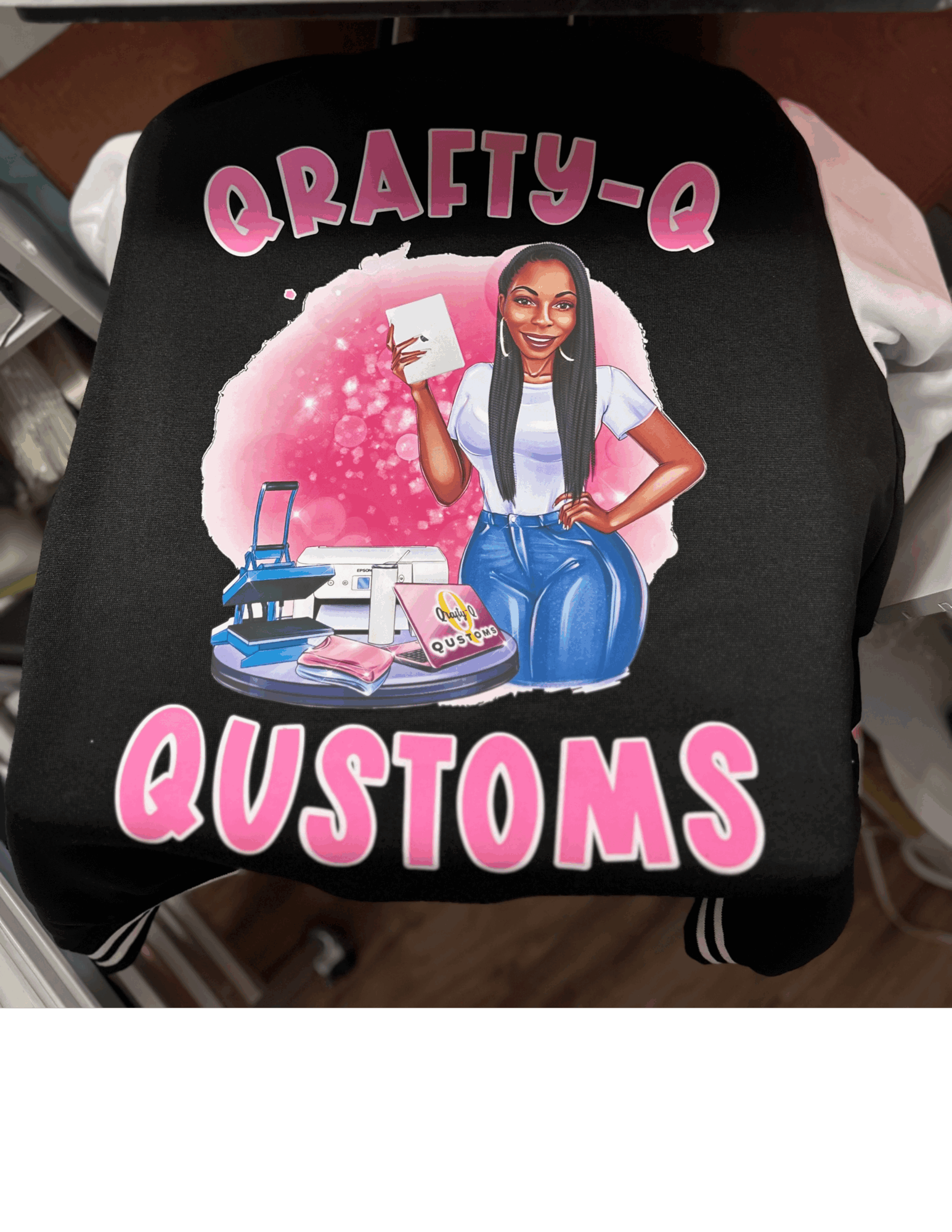 Black bag with colorful illustration of a woman holding a phone, surrounded by crafting supplies, and text reading 'Crafty-Q Customs'.