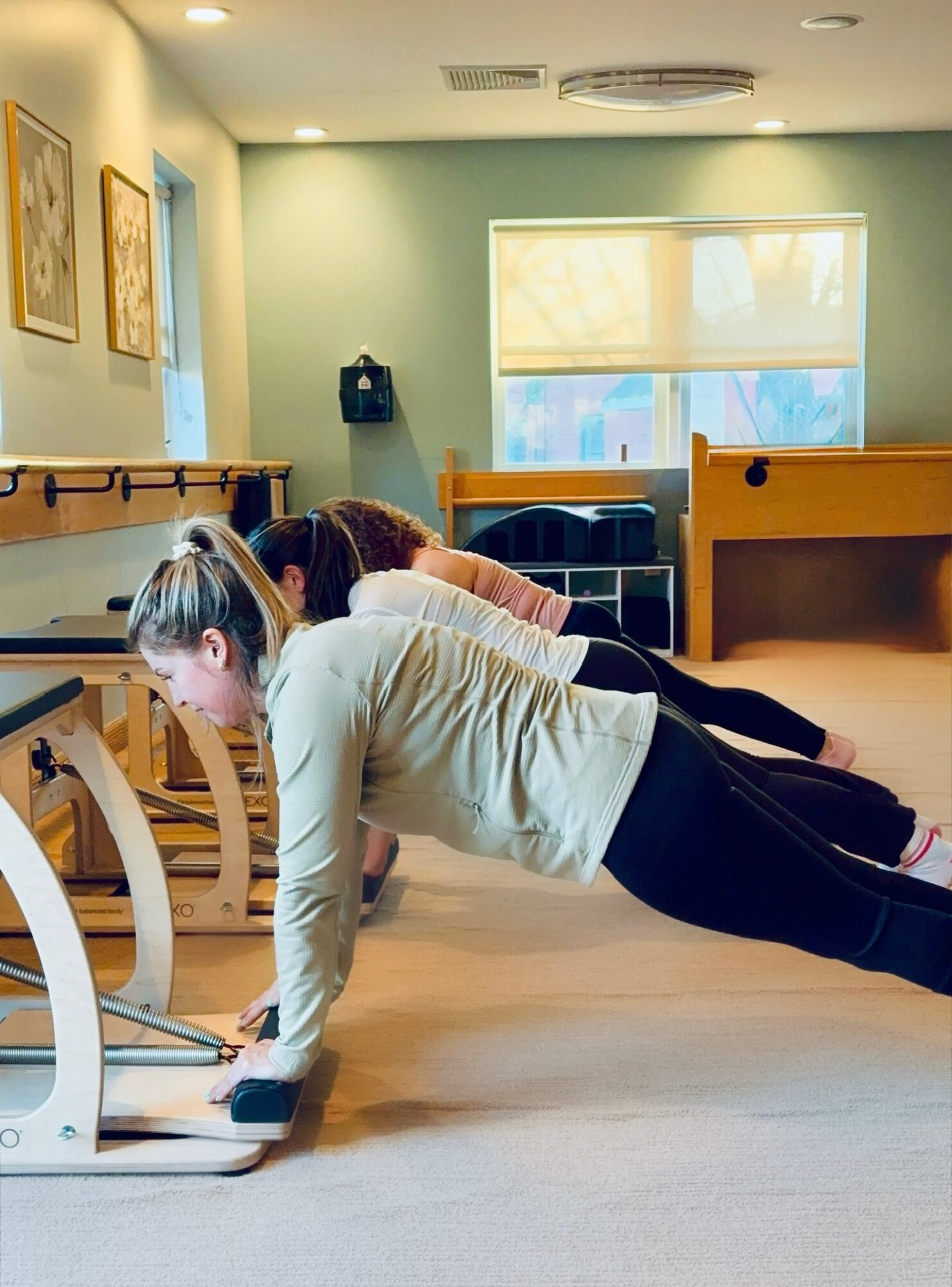 Person doing push-up on a laptop in a room with large window, wooden furniture, and artwork on walls.