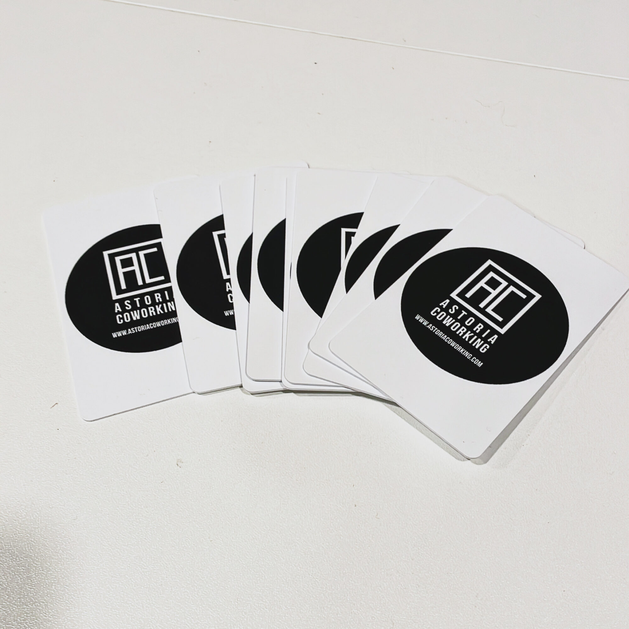 Stack of cards with black and white logo reading 'Astoria Coworking' on a white surface.