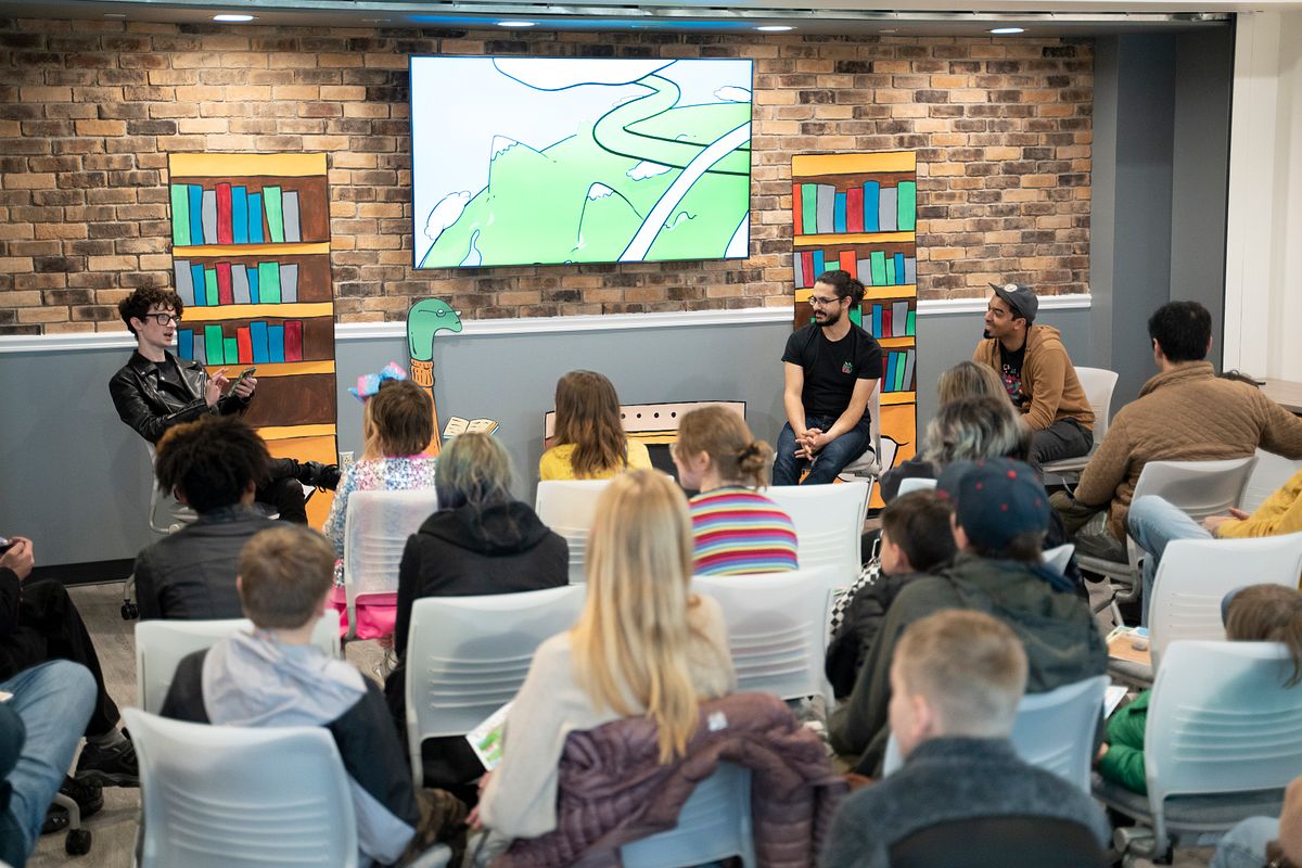 Panel discussion with four people in front of an audience in a room with brick walls and bookshelves.