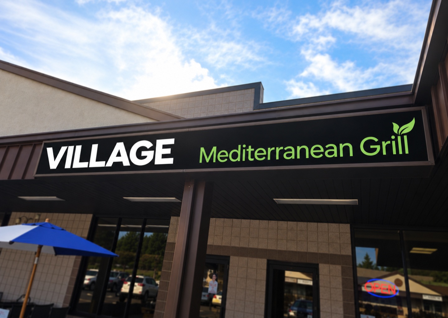 Sign for Village Mediterranean Grill with blue sky and building in background.