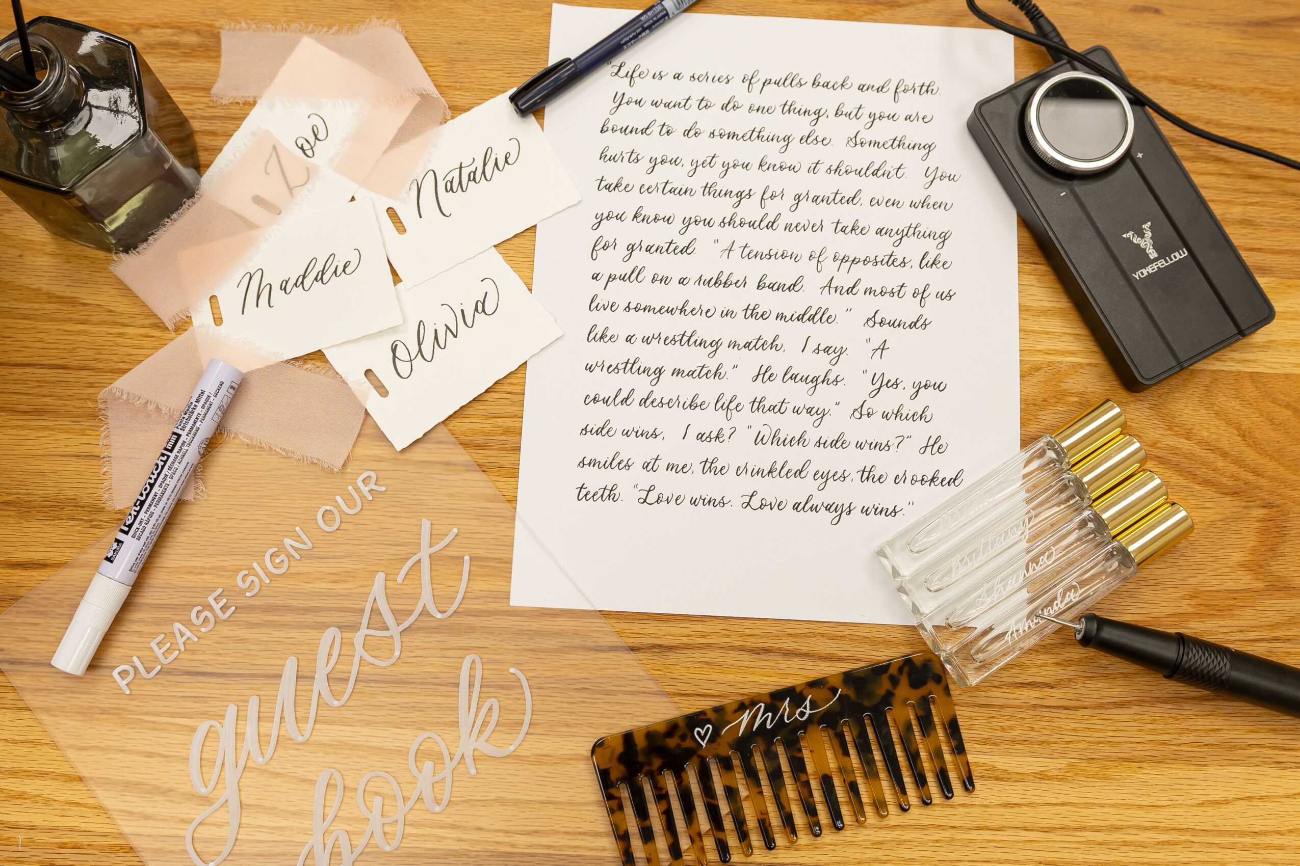 A wooden desk with a handwritten note, a pen, a keychain, a hair comb, and paper notes, some with cursive writing.