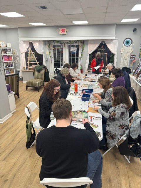 People gathered around a table with informational materials in a room with large windows and wooden floors.