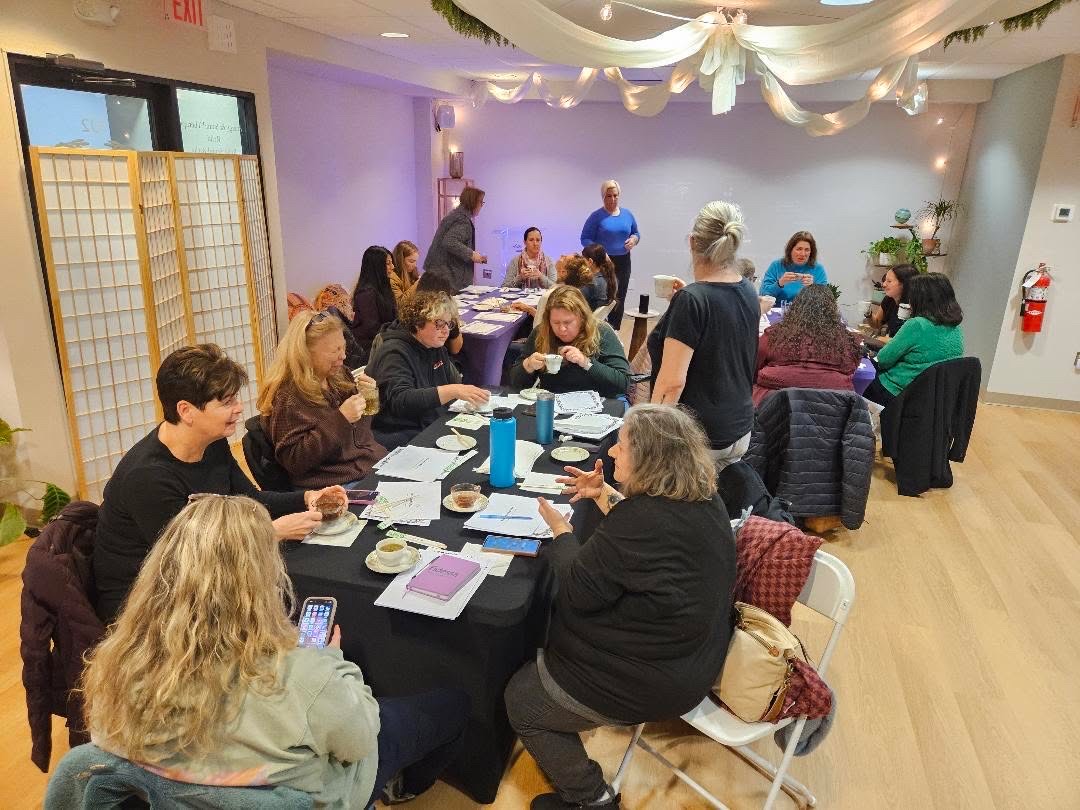 Group of people sitting around tables in a decorated room, engaging in conversation and activities.