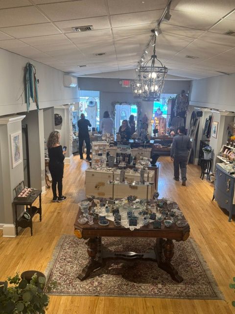 Elegant event space with tables, chairs, and people mingling, decorated with floral arrangements and candles, hardwood floor, and large windows.