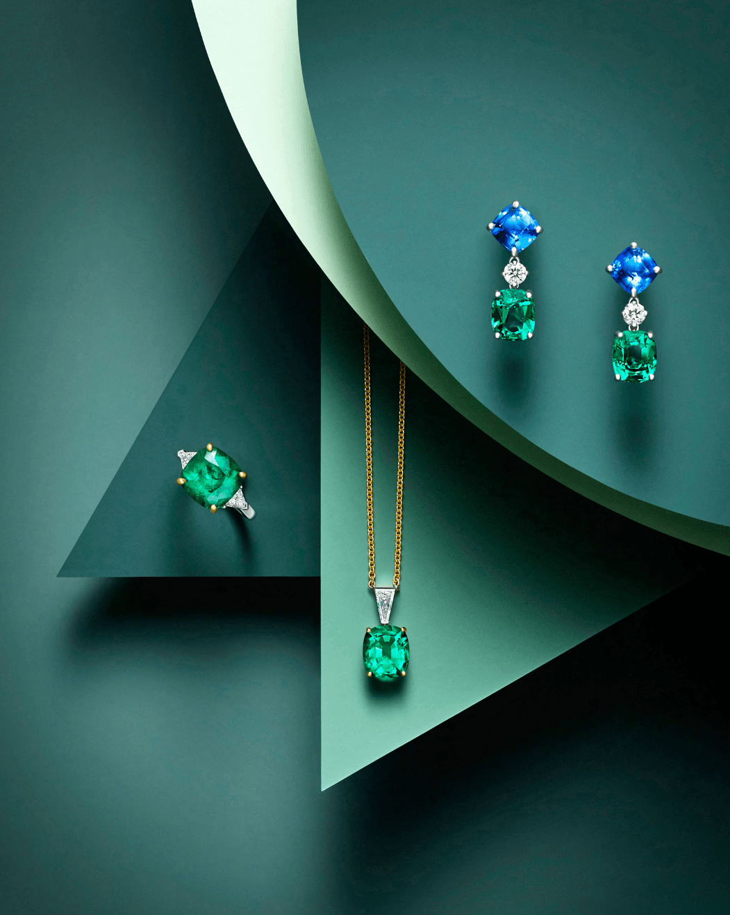 Jewelry display with a green gemstone pendant necklace and matching earrings on a layered green background.