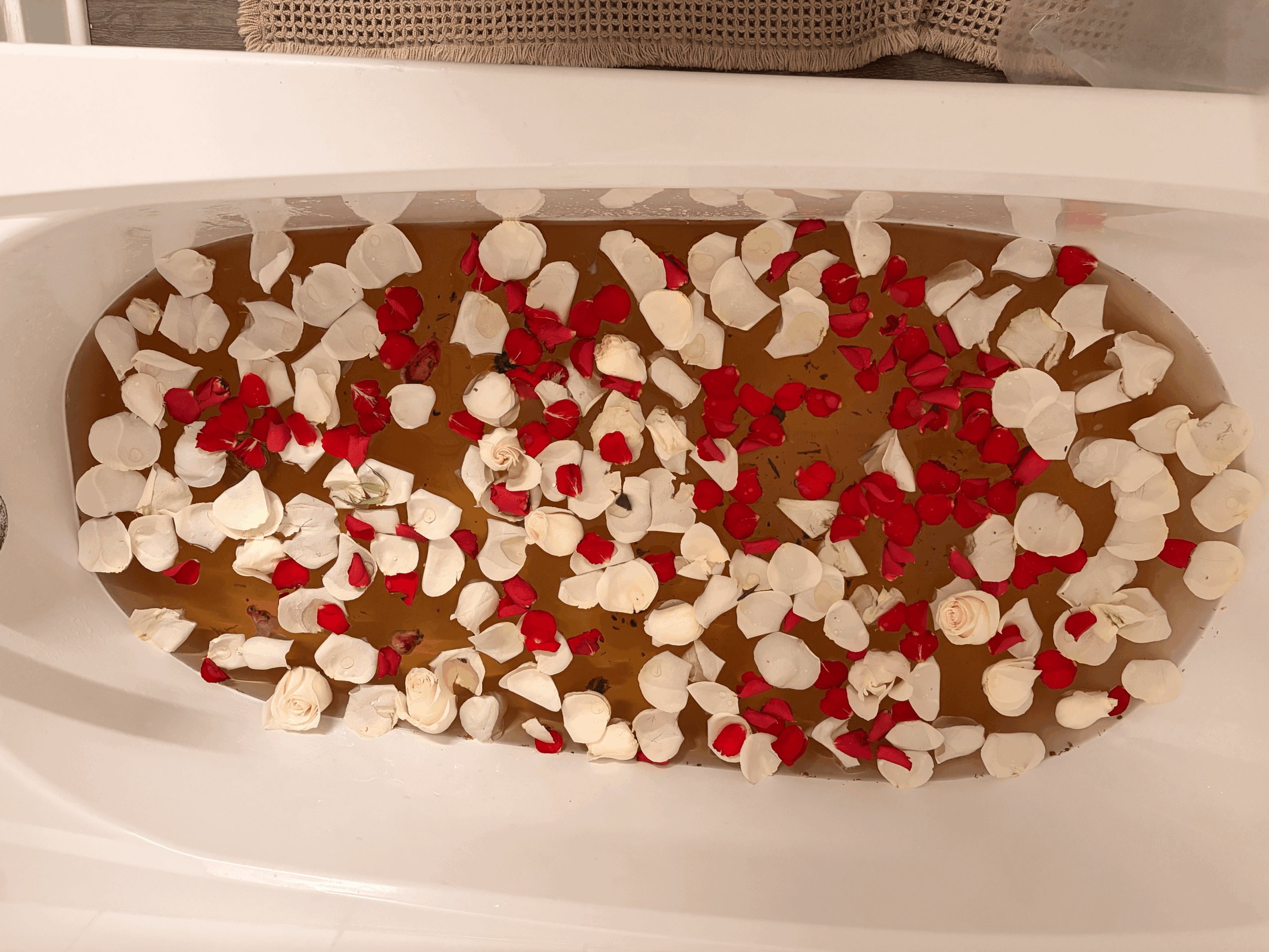 Container filled with hot chocolate topped with marshmallows and red sprinkles, viewed from above.